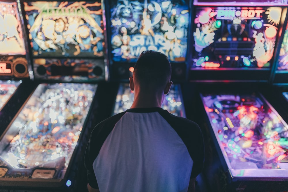 a man standing in front of a bunch of pinball machines