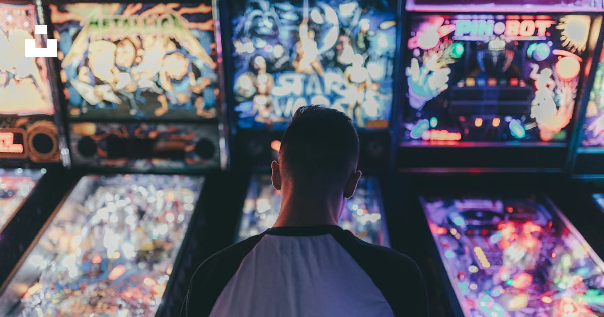 A man standing in front of a bunch of pinball machines photo – Free ...
