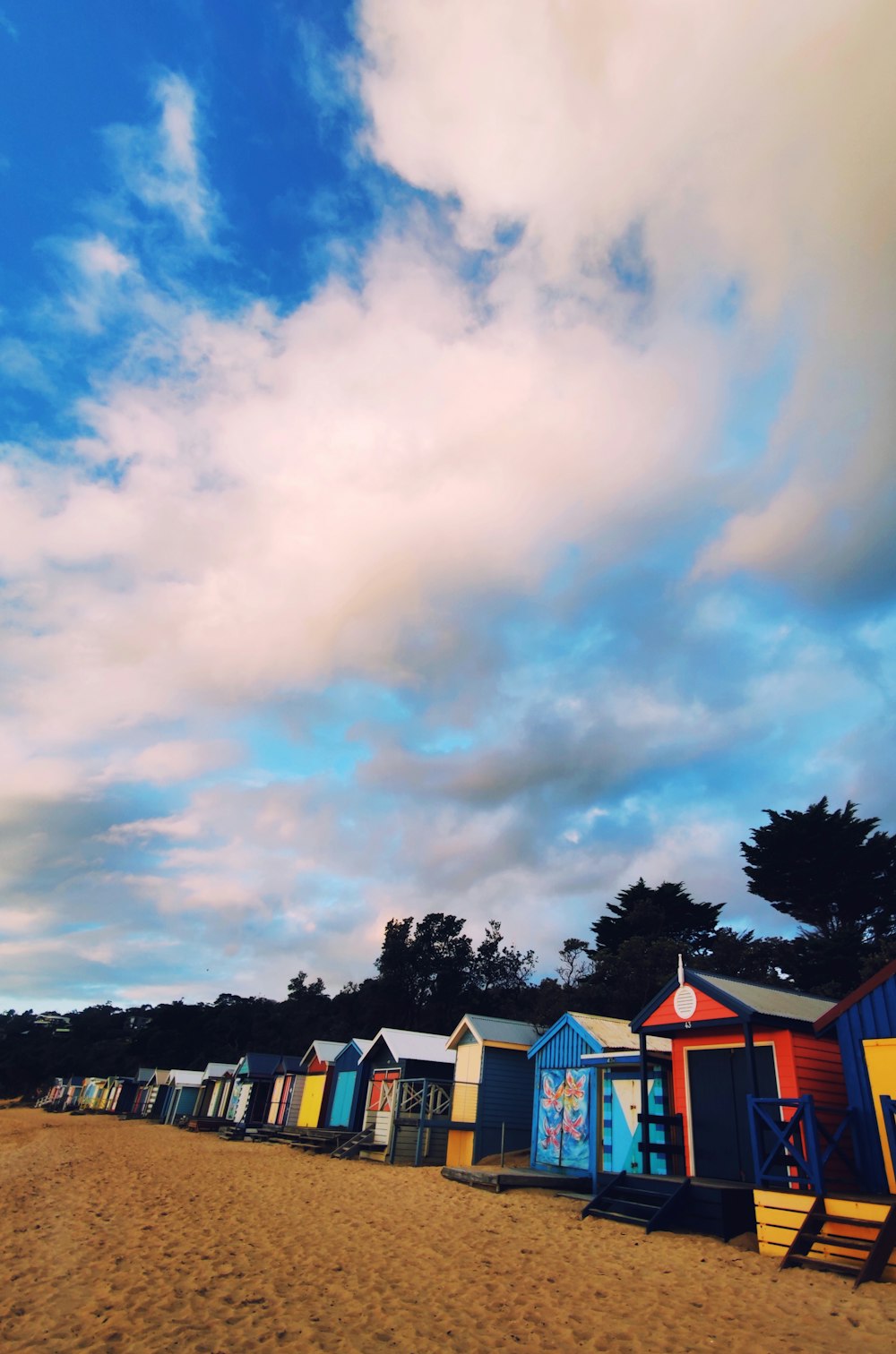 a row of beach huts sitting on top of a sandy beach