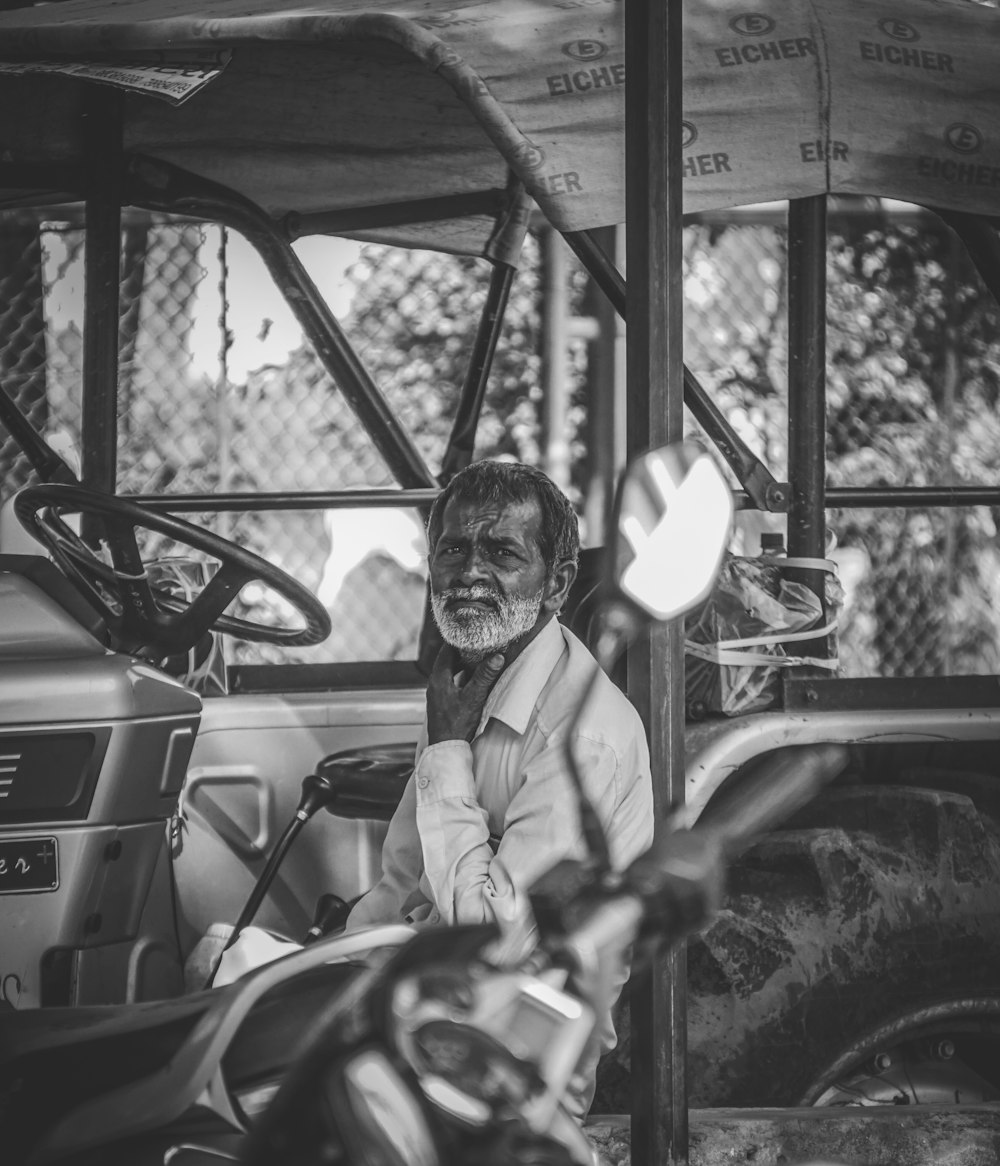 a black and white photo of a man sitting in a vehicle