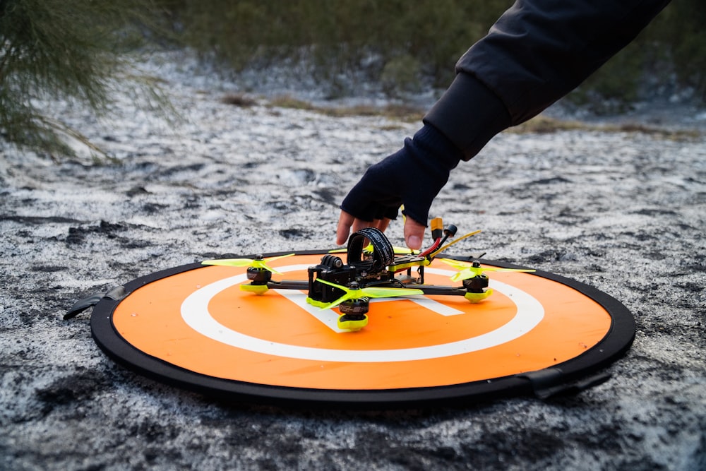 a person holding a remote control helicopter on top of a field