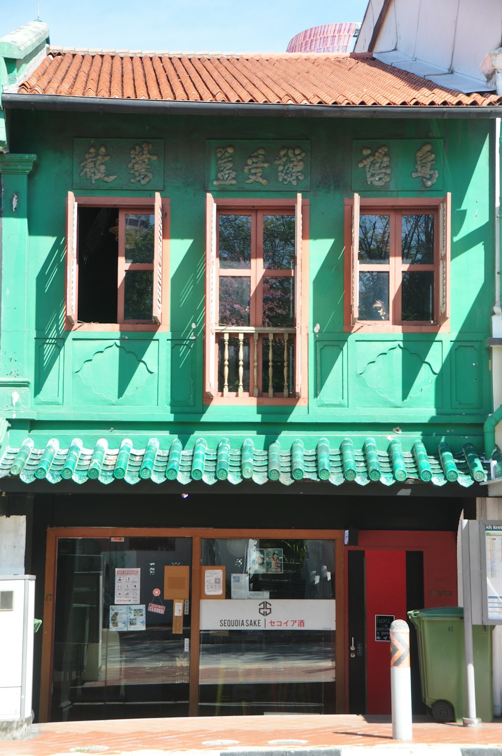 a green building with a red door and windows