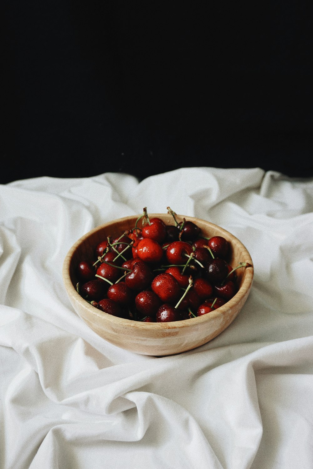 a bowl of cherries on a white cloth