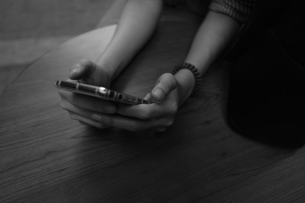 Una persona sentada en el suelo sosteniendo un teléfono celular