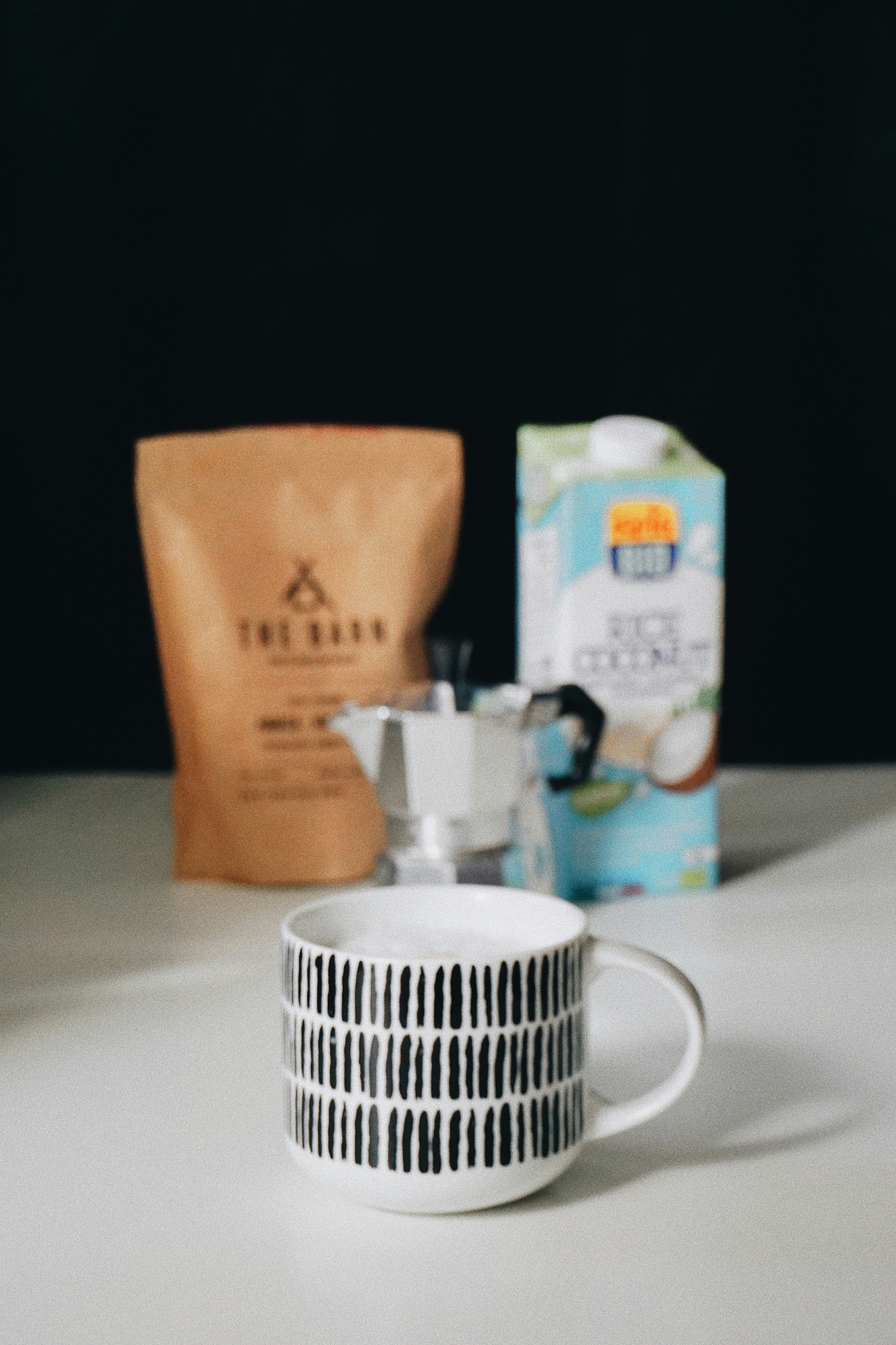 a coffee cup sitting on top of a table next to a bag of coffee