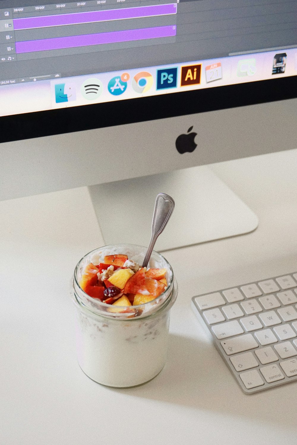 una taza de yogur con una cuchara sentada frente a una computadora