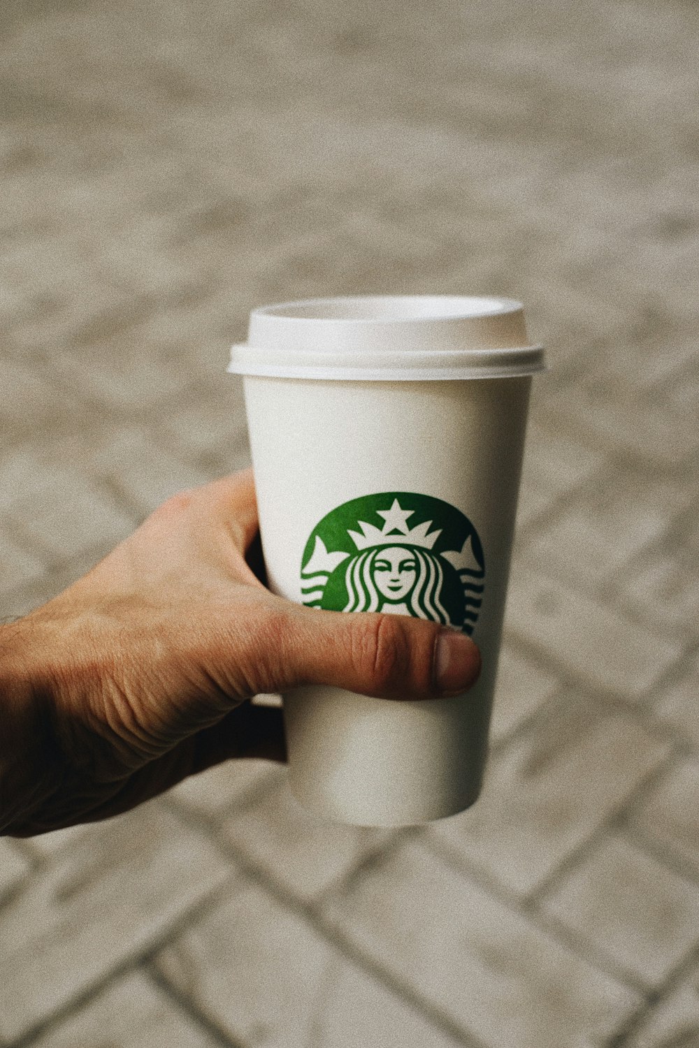 a person holding a cup of starbucks coffee