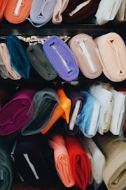 a bunch of different colors of cloth on a shelf