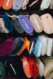 a bunch of different colors of cloth on a shelf