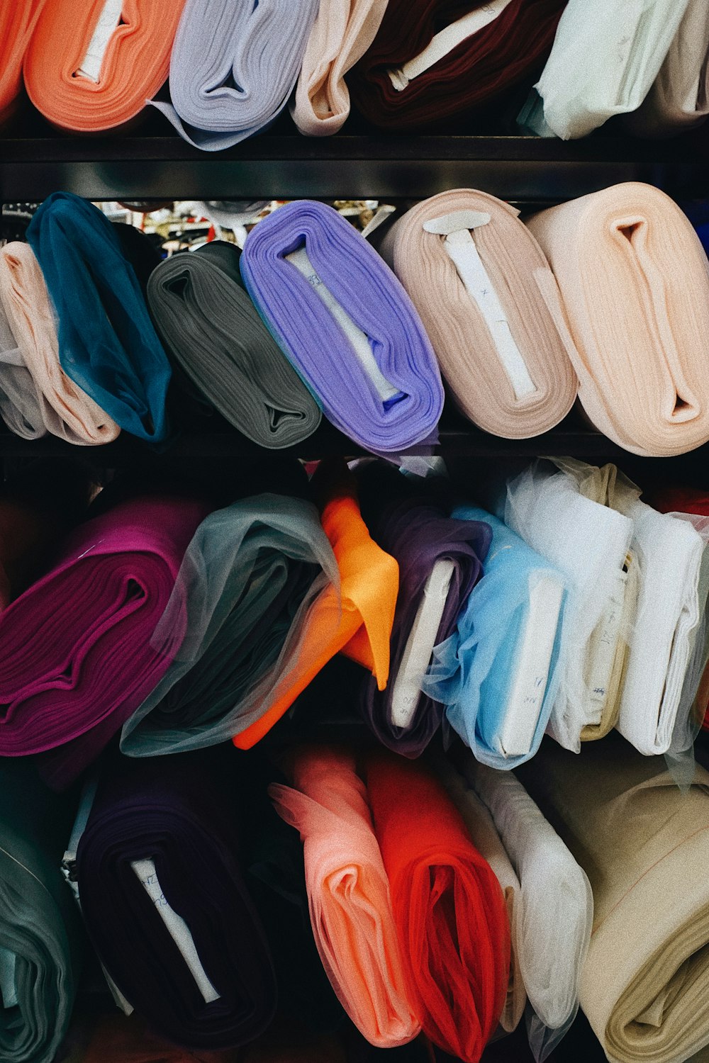 a bunch of different colors of cloth on a shelf