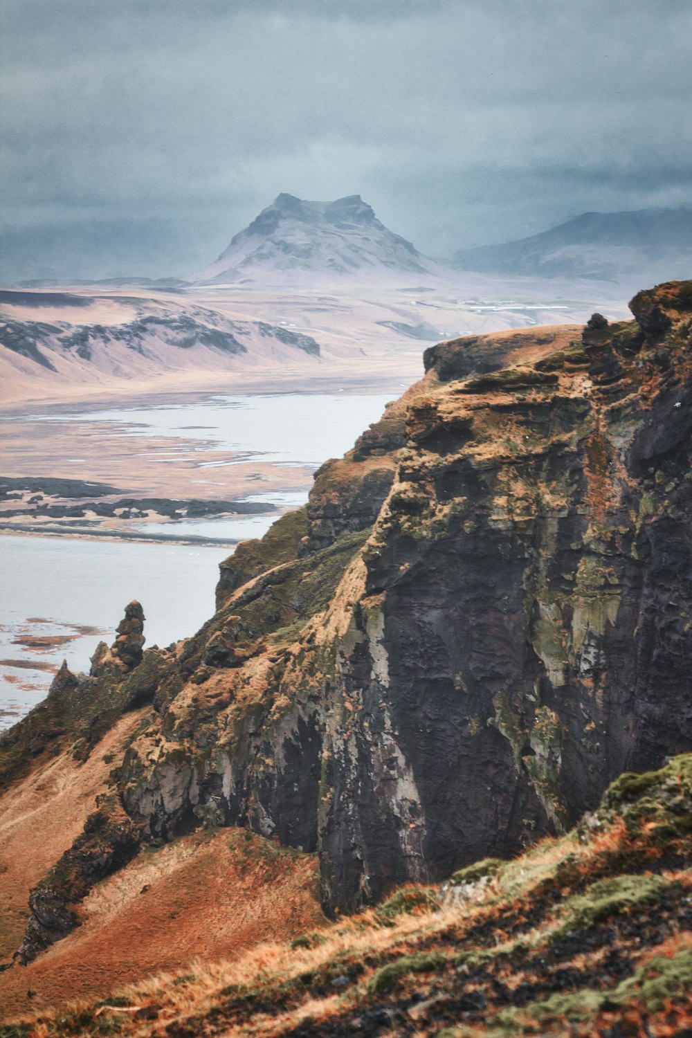 a sheep standing on top of a mountain next to a body of water