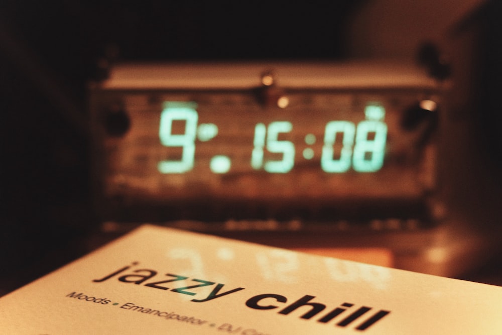 a close up of a clock with a book in front of it