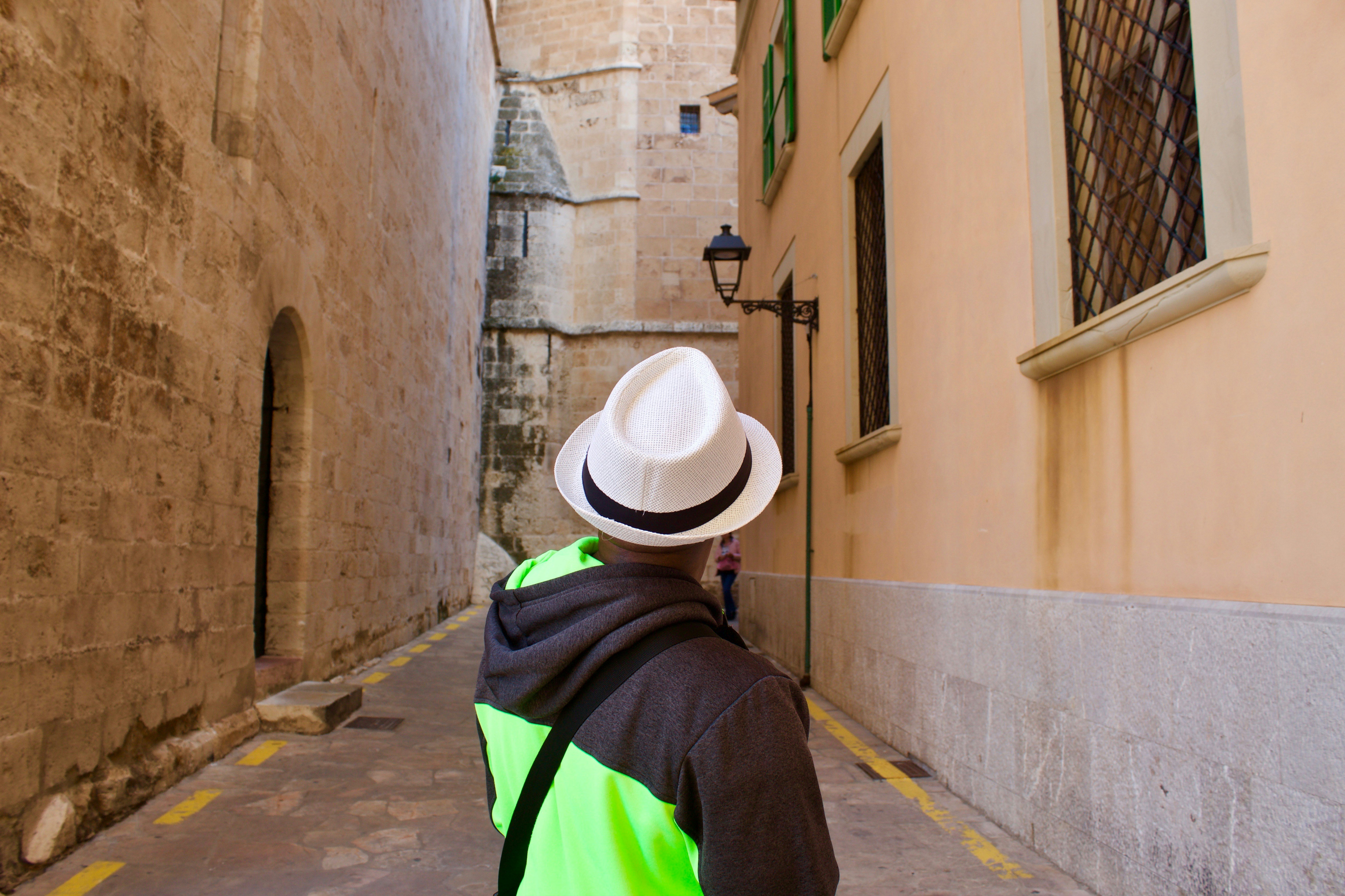 a person wearing a hat and a jacket walking down a street