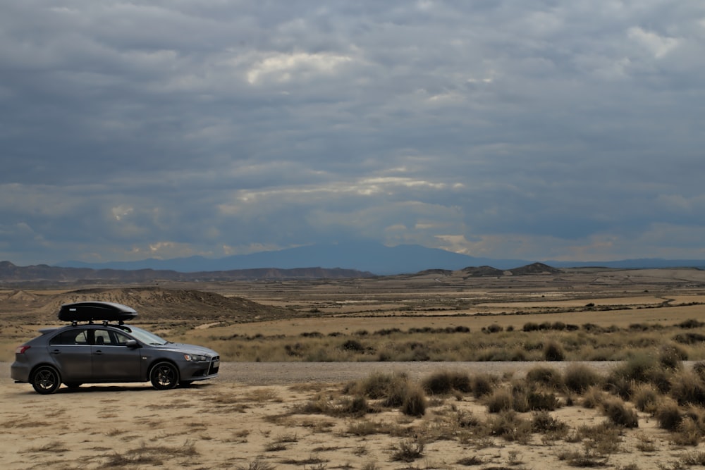 un'auto con una tavola da surf sopra parcheggiata nel deserto