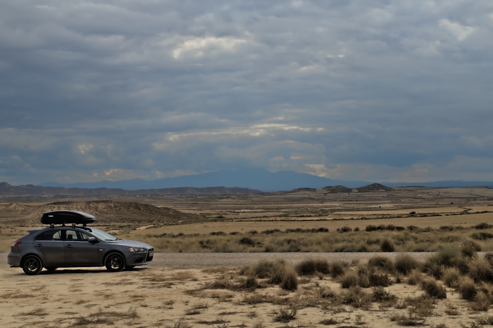 a car with a surfboard on top of it parked in the desert