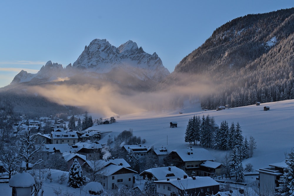 a snow covered mountain range with a village in the foreground