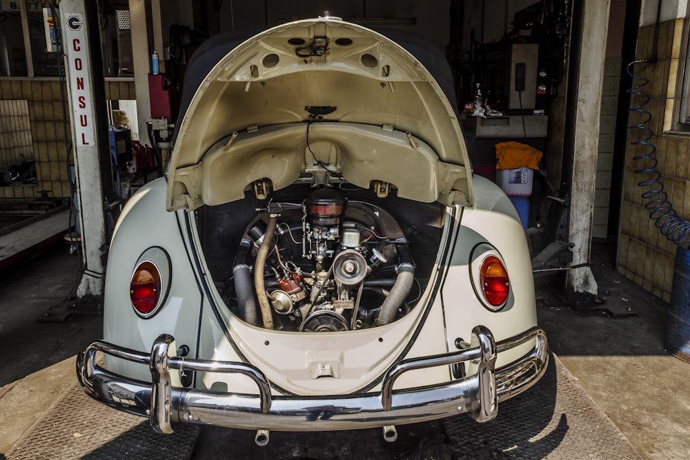 a white vw bug with a engine in the trunk