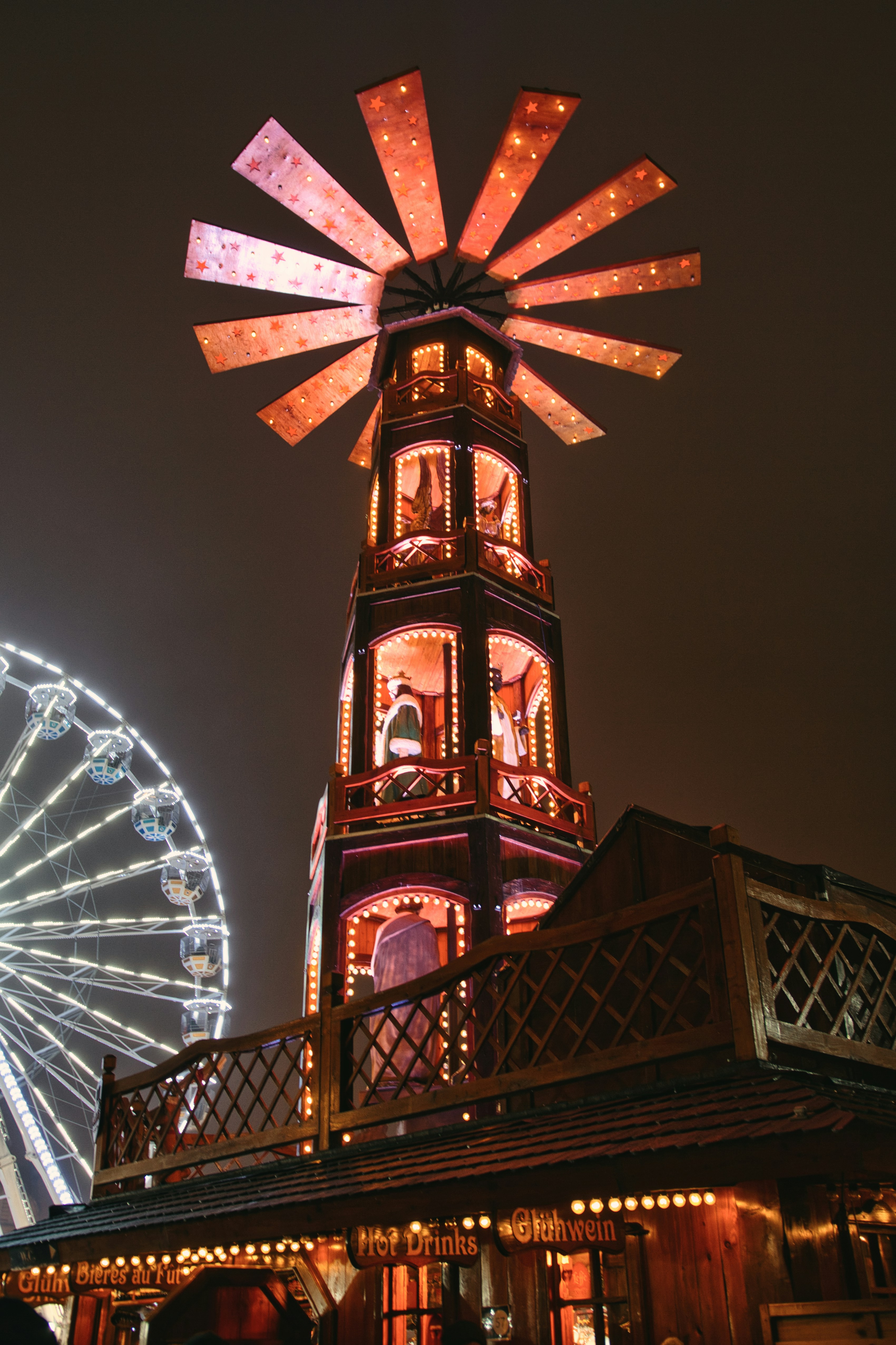 a ferris wheel lit up at night with a ferris wheel in the background