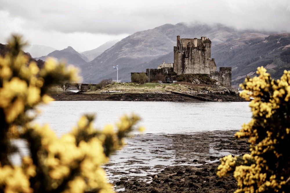 a castle sitting on top of a mountain next to a body of water