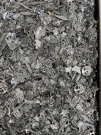 A collection of expressive charms laid out on a rustic wooden table, showing their unique shapes.