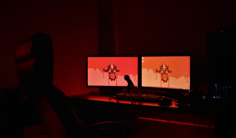 two computer monitors sitting on top of a desk