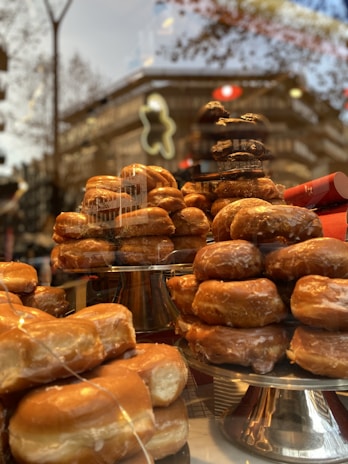 A warm, inviting donut shop exterior nestled among towering pine trees at dawn.