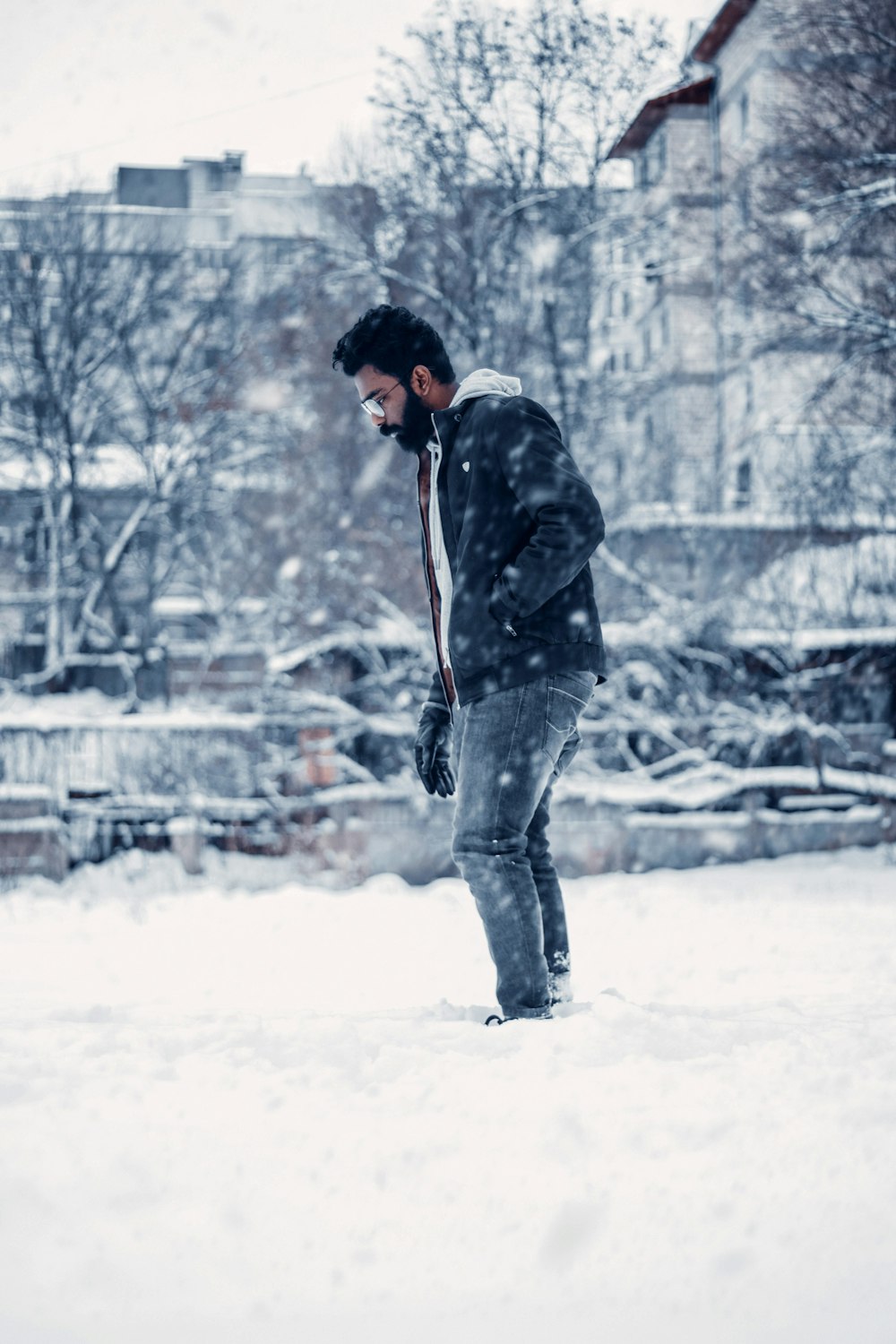 a man standing in the snow with his foot on a snowboard