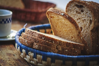 a close up of bread in a basket with a cup of coffee