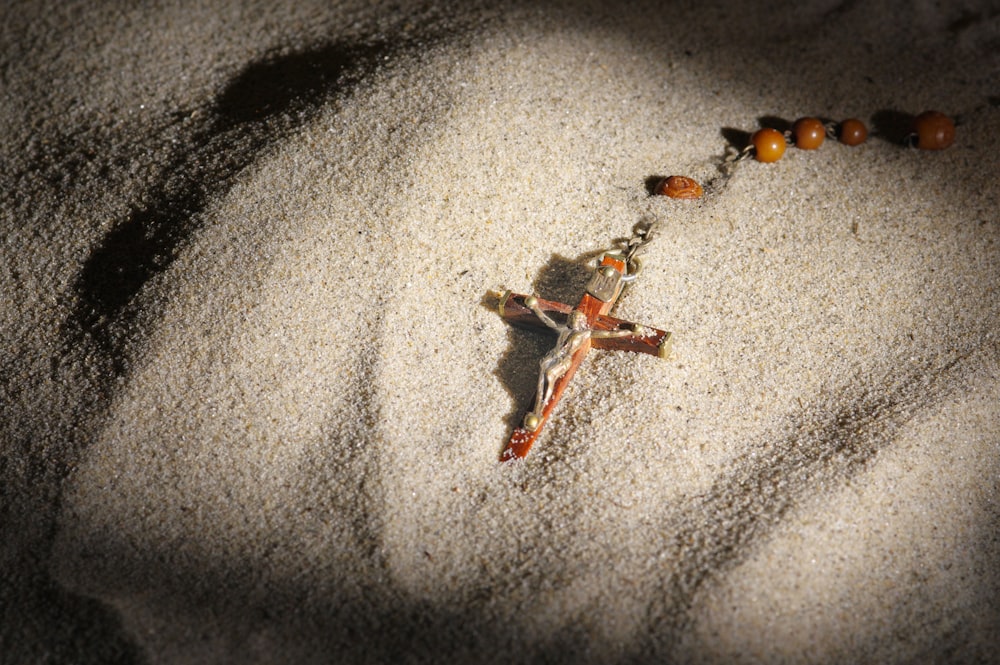 a rosary laying on top of a sandy ground