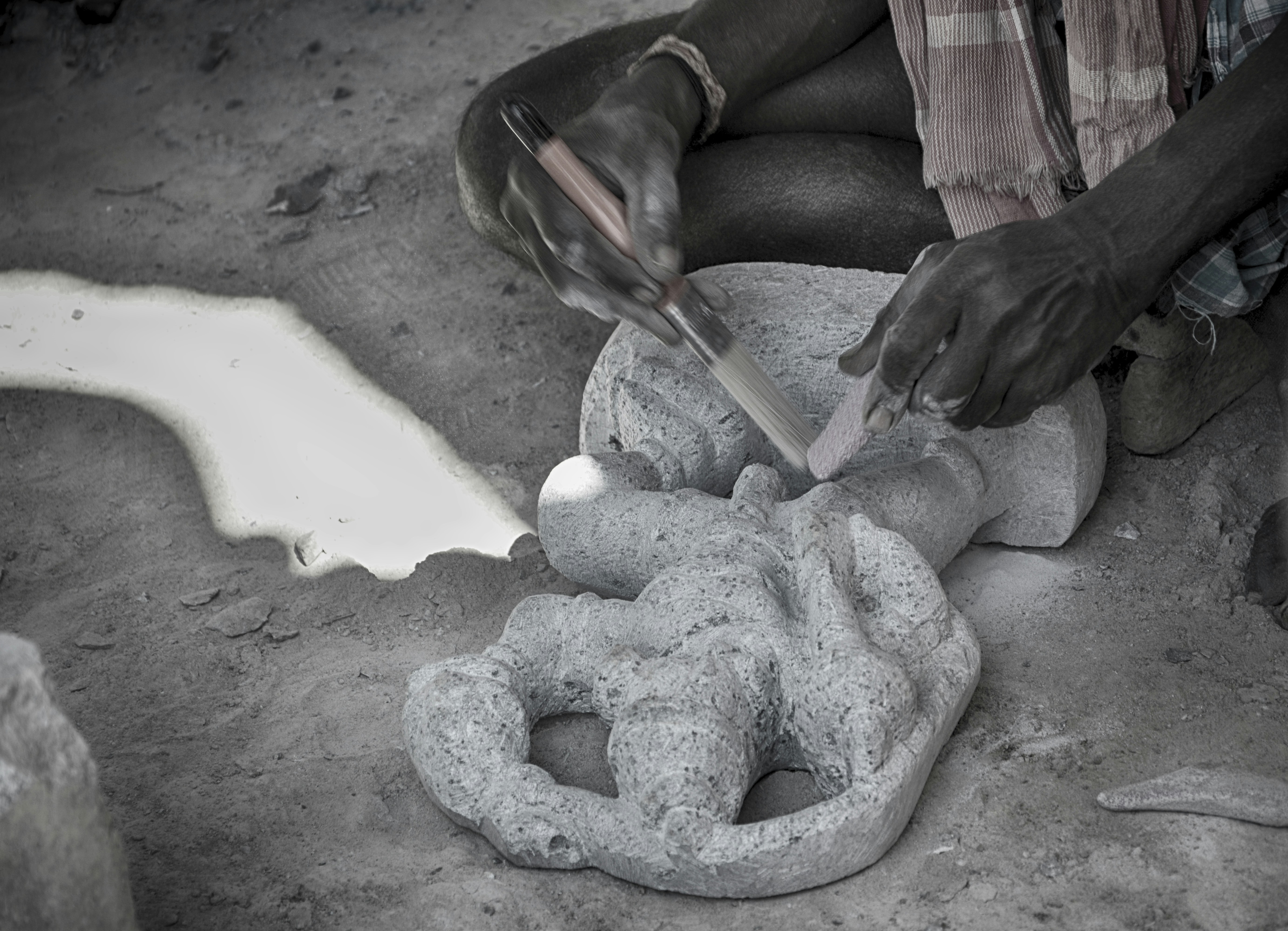 Un uomo sta scolpendo una statua di cemento