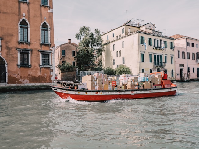 a red boat with boxes on it in the water