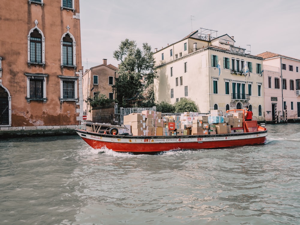 a red boat with boxes on it in the water