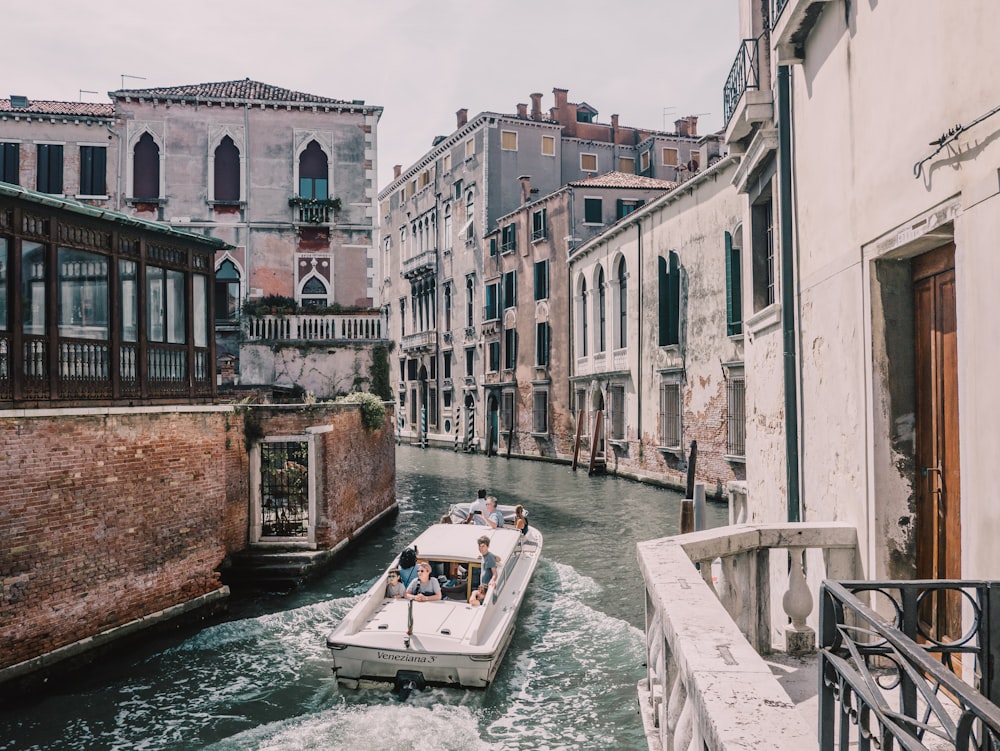 a boat traveling down a river next to tall buildings