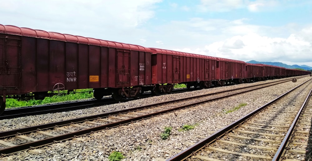 a long red train traveling down train tracks