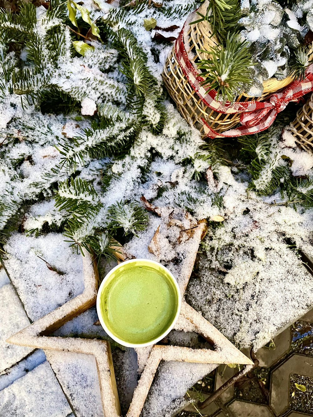 a cup of green liquid sitting on top of a snow covered ground