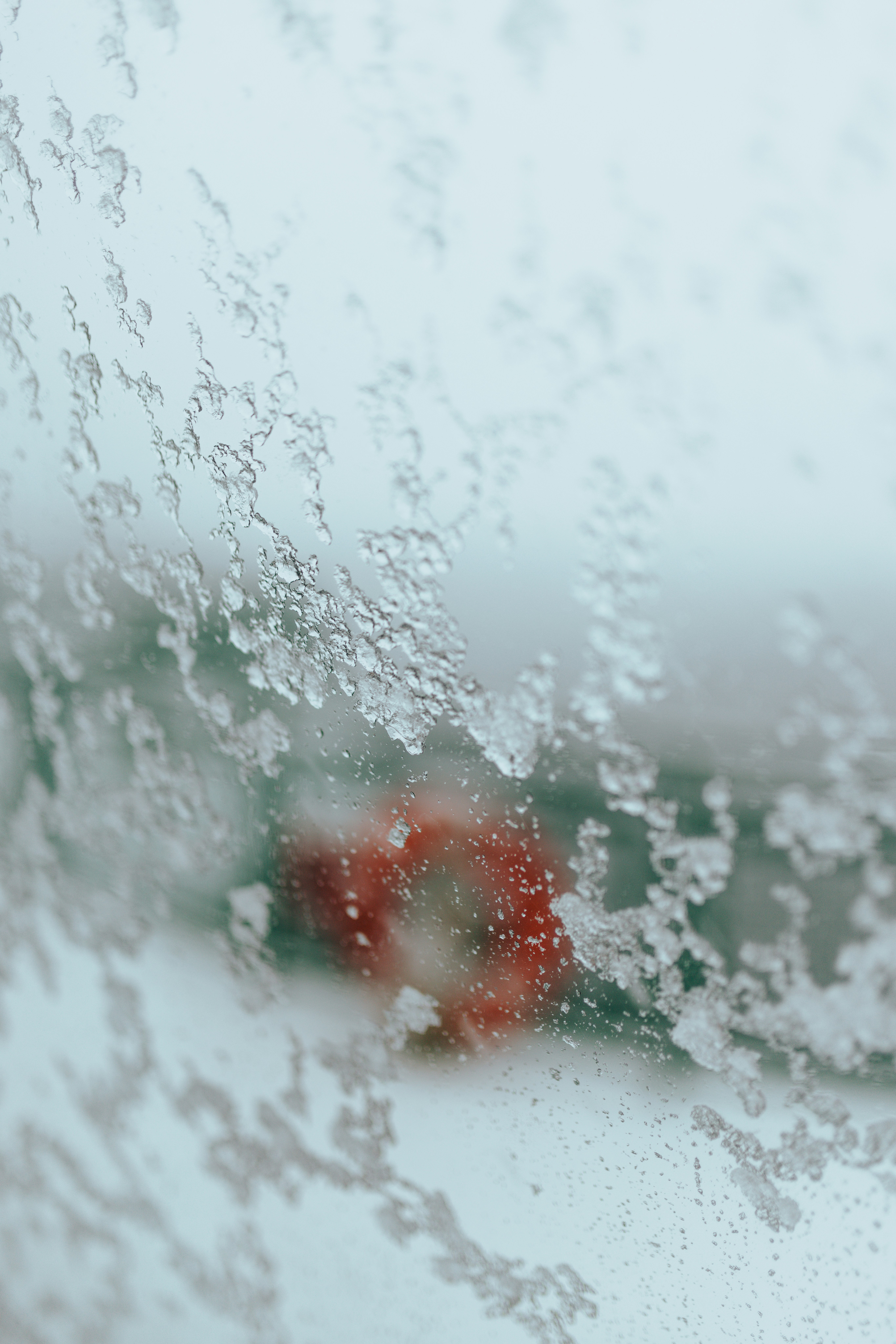 a red object sitting on top of a window covered in rain