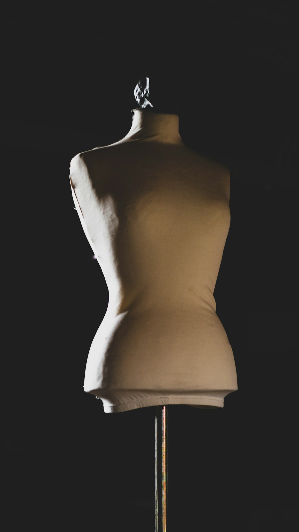 a mannequin on a stand with a black background