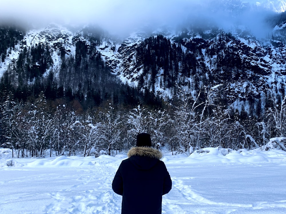 a person standing in the snow looking at a mountain
