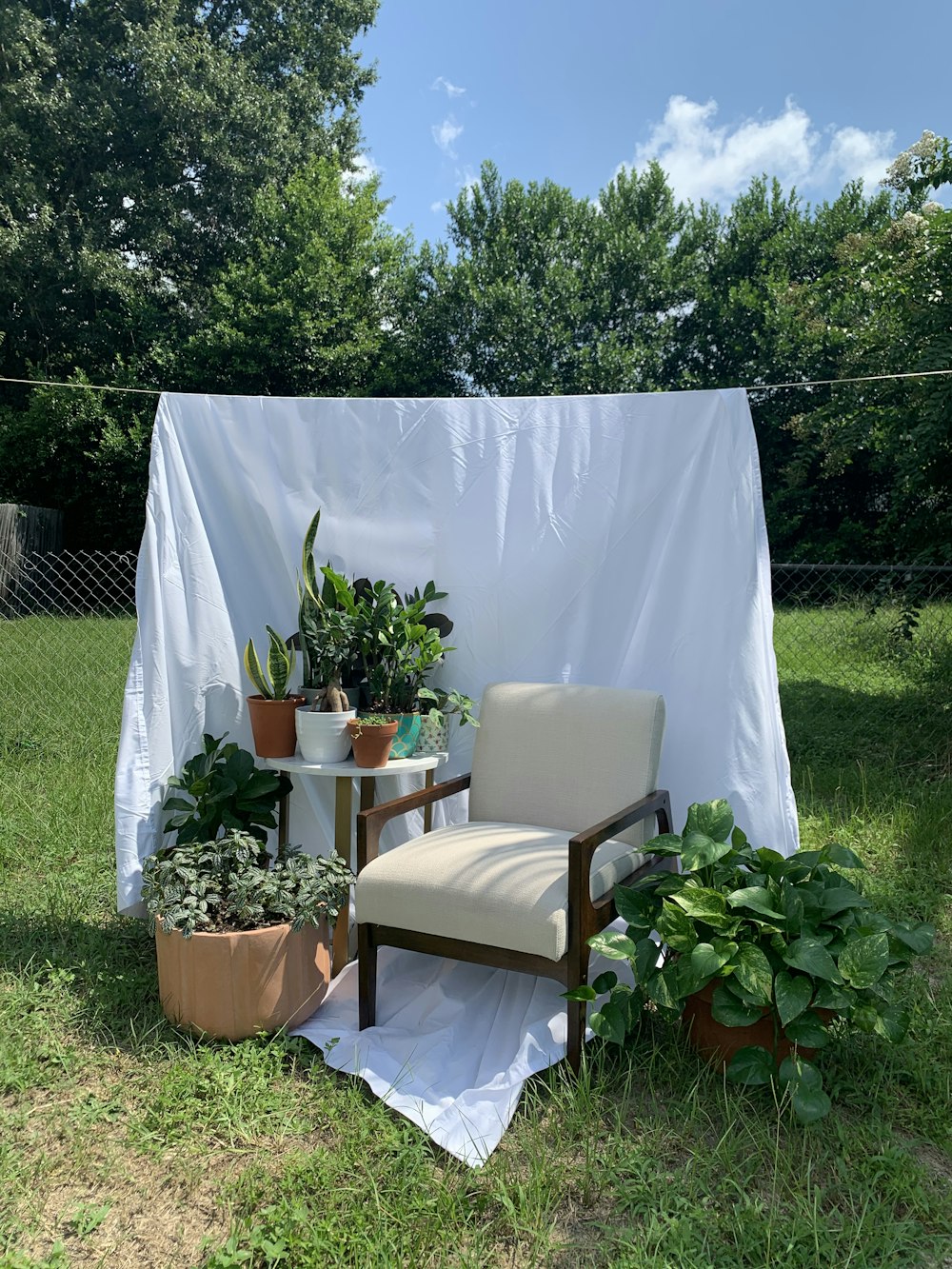 a chair sitting in the grass next to a table with potted plants