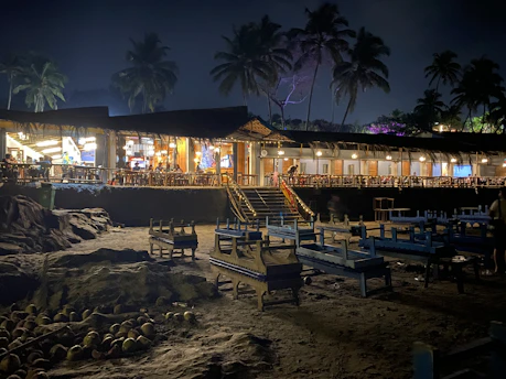 A cozy beachside café at sunset with colorful tables and palm trees.