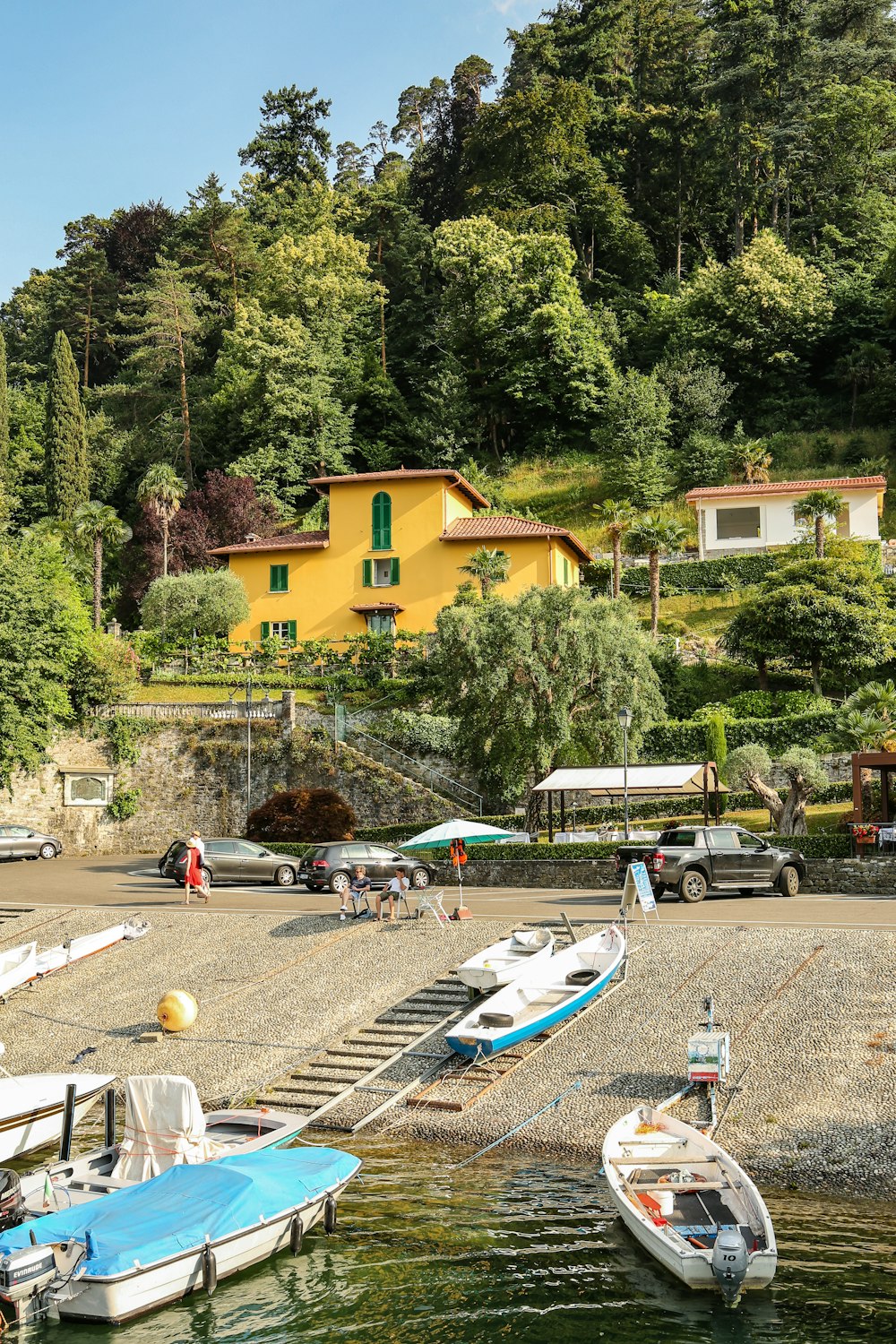 a group of boats parked on a beach next to a yellow house