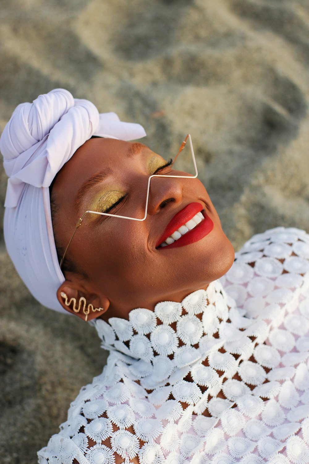 a woman wearing a white top and gold eye makeup