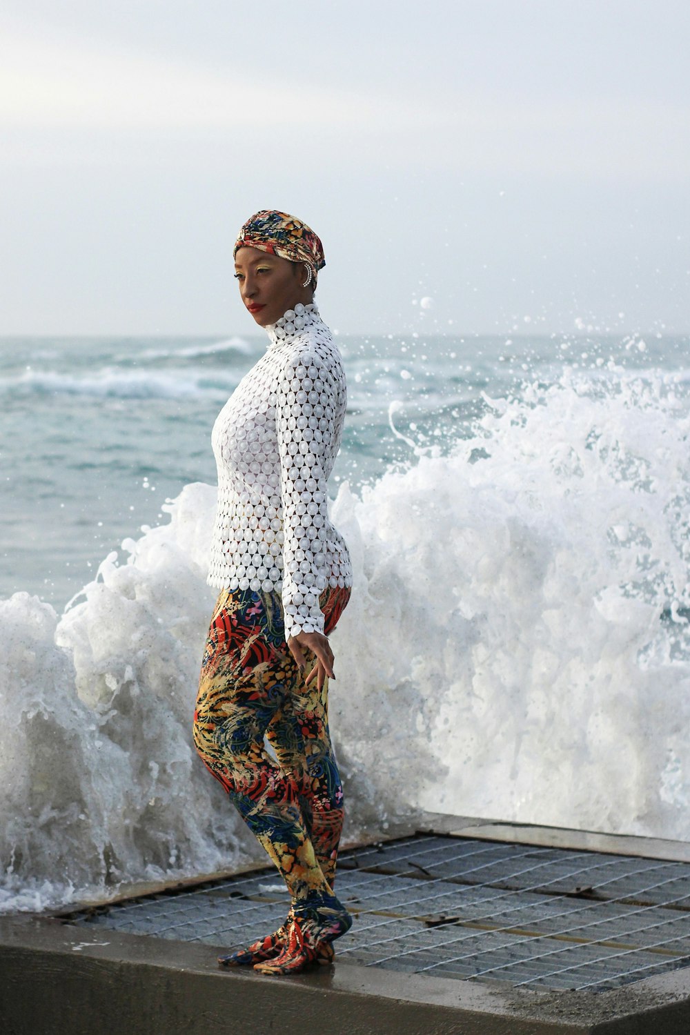 a woman standing on a ledge next to the ocean