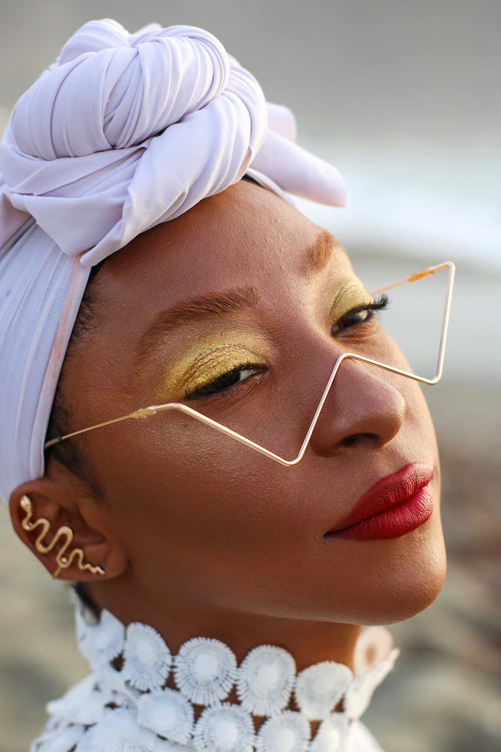 a woman with a white turban and gold eye makeup