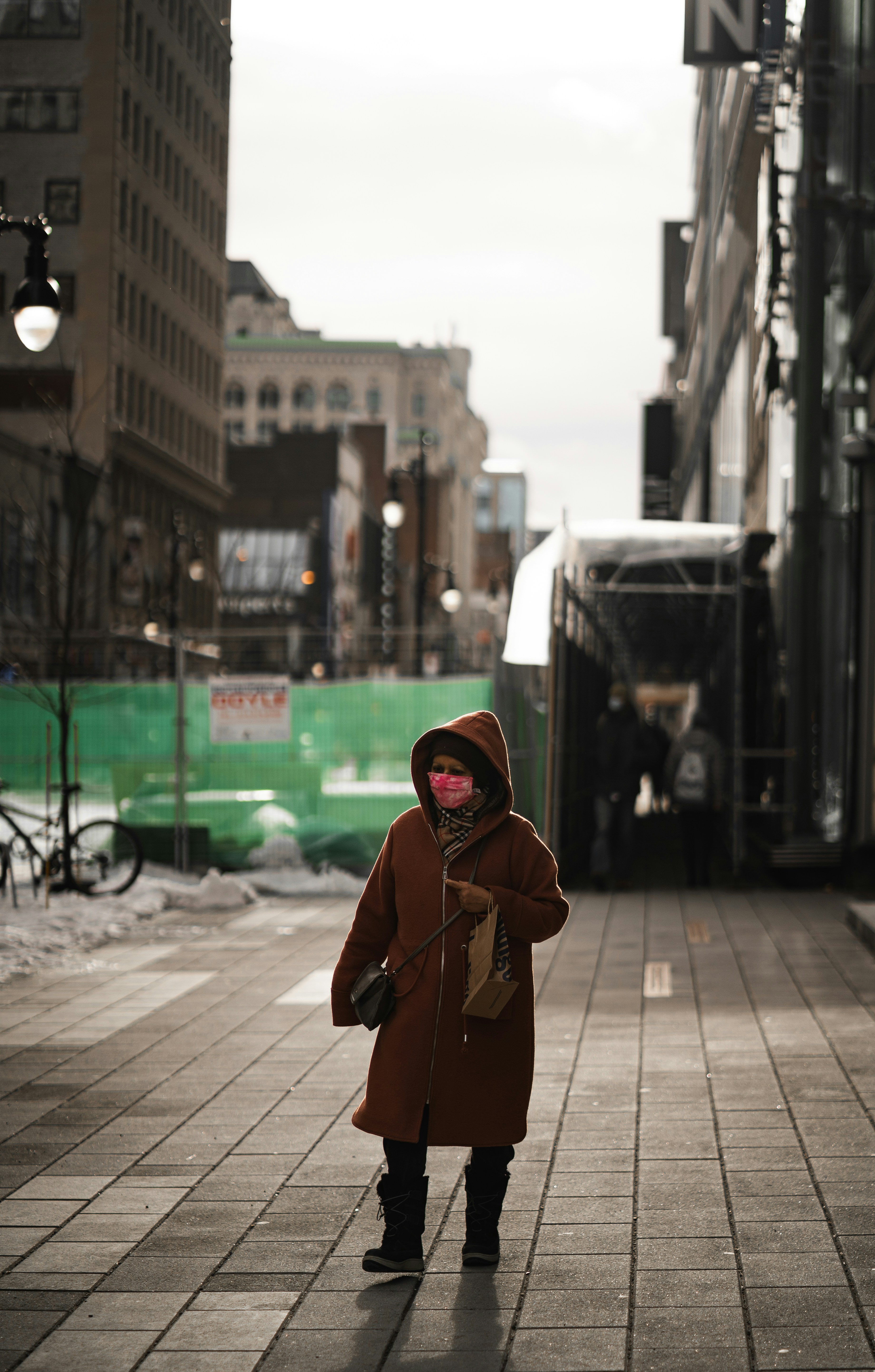 A little girl in a brown coat is walking down the street photo – Free ...