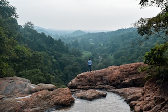 a man standing on top of a rock next to a river