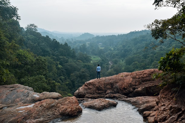 a man standing on top of a rock next to a river
