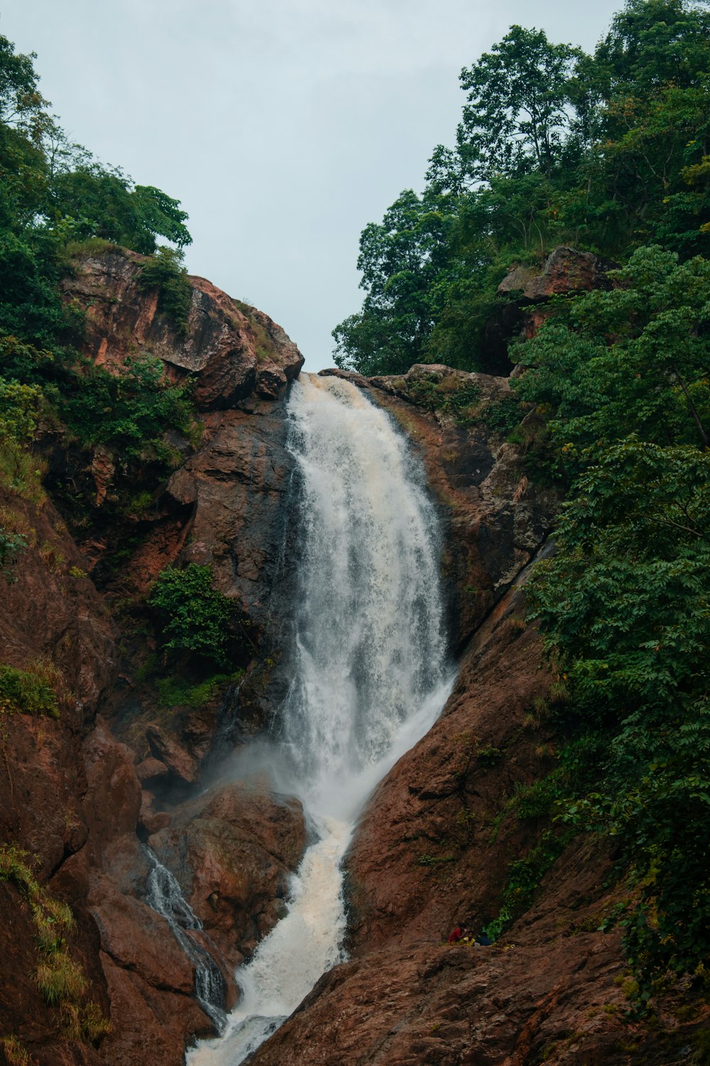 a very tall waterfall in the middle of a forest