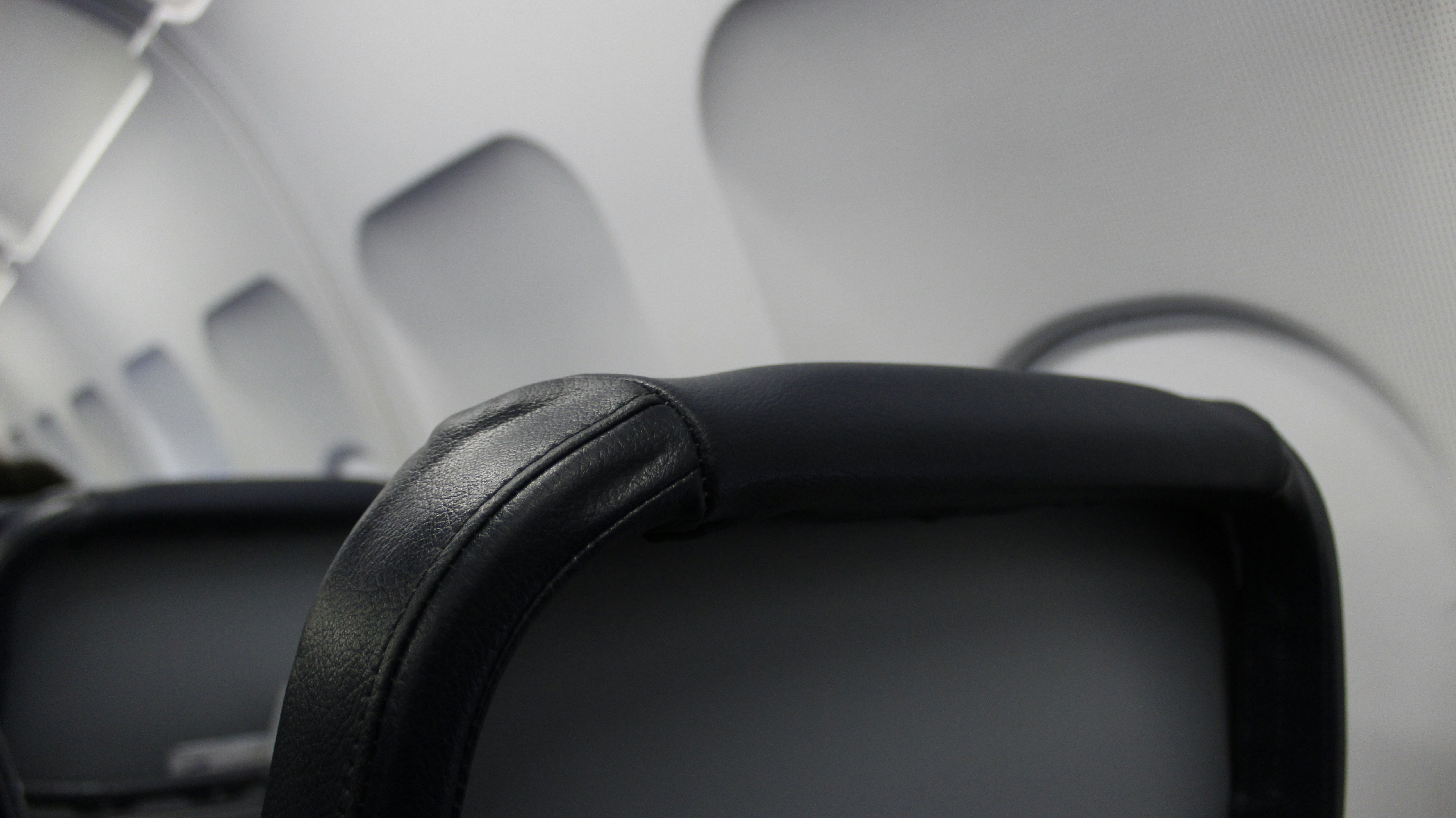 the back of an airplane seat with a television on it, Economy class of airplane. Empty seats.