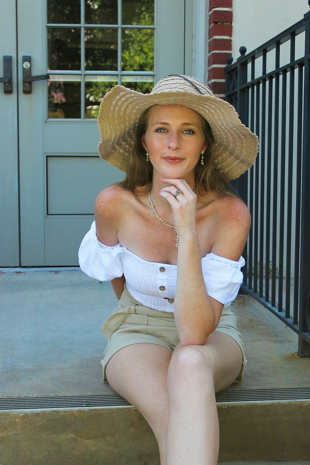 a woman sitting on the steps wearing a hat